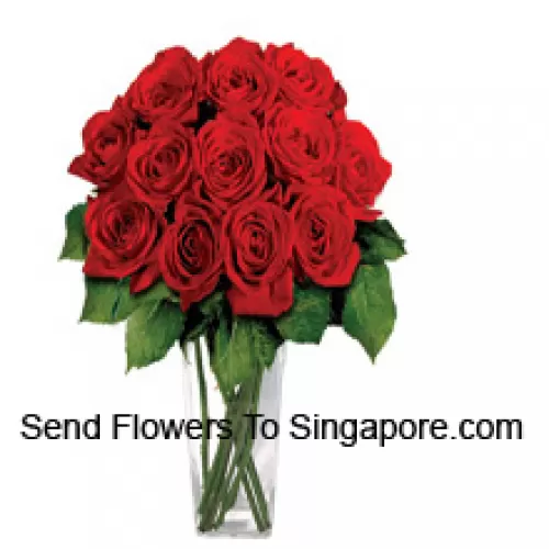 15 roses rouges avec quelques fougères dans un vase en verre