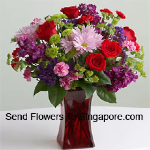 Roses rouges, œillets roses et autres fleurs saisonnières assorties dans un vase en verre